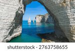Framed perspective of the Needle and Aval Arch through the massive Manneporte natural arch in Etretat, Normandy, France