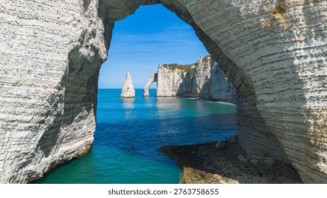 Framed perspective of the Needle and Aval Arch through the massive Manneporte natural arch in Etretat, Normandy, France