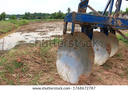 A frameset of three disc plough placed beside the rice fields.