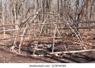 The framework and basic structure of a Native American lodge made with bent saplings; a fireplace is in the lodge.