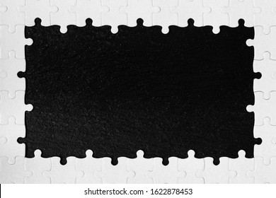 Framing in the form of a rectangle, made of a white jigsaw puzzle. Frame text and jigsaw puzzles. Frame made of jigsaw puzzle pieces on black background.