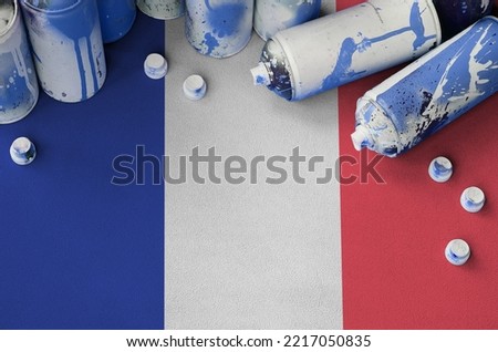 France flag and few used aerosol spray cans for graffiti painting. Street art culture concept, vandalism problems