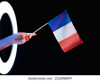 France Flag. Patriotic Symbol. Culture Pride. Female Hand Holding Tricolor With Blue White Red Three Vertical Stripes In LED Light Ring Isolated On Black Background.