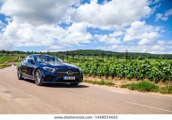 France Lyon 2019-06-20 closeup front view luxury\
dark blue German car sedan premium Mercedes CLA with EU\
registration number on road at french vineyards. Concept wine\
travel in Beaune,\
Burgundy