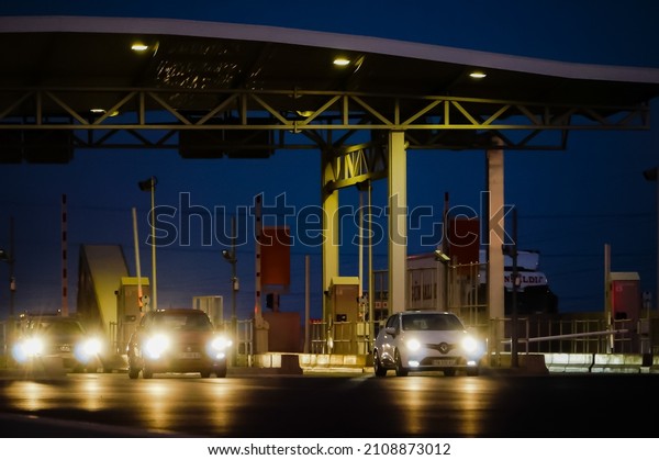 Saint-Jean-de-Védas, France - Oct. 2021 - Cars with\
lights on, by night, driving through the toll gate of Montpellier\
2, at the end of the highway A709 and at the start of the A9, which\
goes to\
Spain