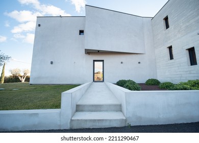 Uzès, France - September The 26th 2021 : Entrance Facade Of A Big White Modern House, Imposing But A Bit Empty, Big White Driveway, Garden And Blue Sky, Small Black Windows