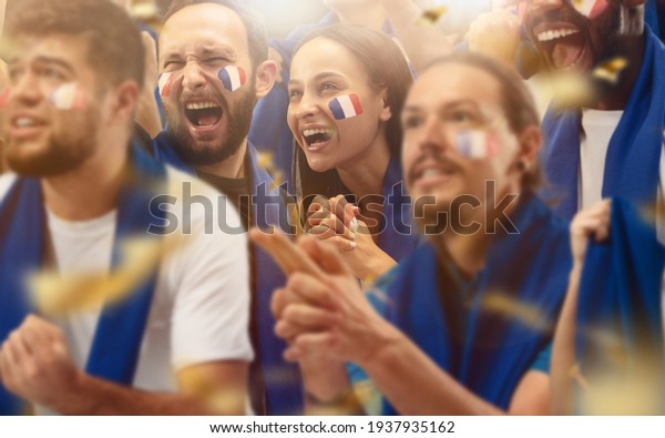 Francian football, soccer fans cheering
their team with a blue scarfs at stadium. Excited fans cheering a
goal, supporting favourite players. Concept of sport, human
emotions,
entertainment.
