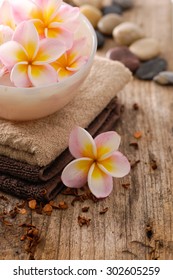 frangipani in bowl and stones ,dry flower petals ,towel on old wood

