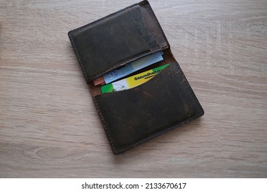 Frankfurt, Germany - January 2022: Leather Wallet With Public Health Insurance Cheaper, Insurance Card In German, Concept Medical Support In Country And On Trip To Europe, Guarantee Of Treatment