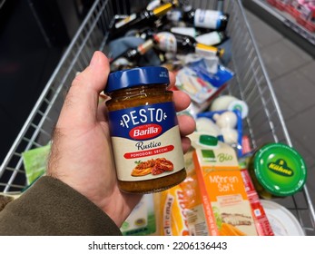 Frankfurt, Germany - Sep 17, 2022: POV Male Hand With Pesto Manufactured By Barilla Above Full Shopping Cart Of Groceries At A Convenience Store