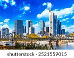 Frankfurt Main Iron footbridge against financial district skyscrapers with blue sky. Skyline cityscape of Frankfurt, Germany during sunny day. Frankfurt is a financial capital of Europe