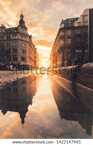 Frankfurt in the morning, looking into a street canyon with sunlight and reflection in a puddle on the street