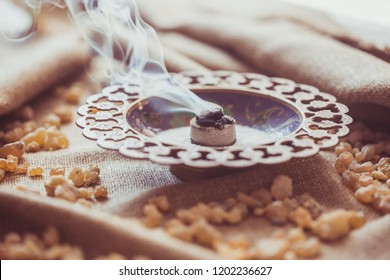 Frankincense burning on a hot coal. Frankincense is an aromatic resin, used for religious rites, incense and perfumes, incense smoke (color toned image)