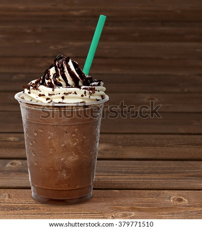 Frappuccino in takeaway cup on wooden table