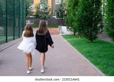 fraternal twins sisters. blonde and brunette teen girls in fashionable black and white clothes outdoors. sisterhood, siblings spending time together
