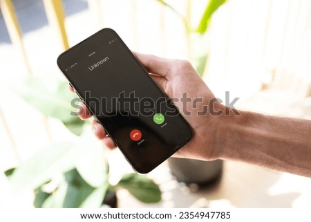 Fraud or fraudulent schemes. Close-up of a male hand holding a phone with an unexpected incoming call from an unknown