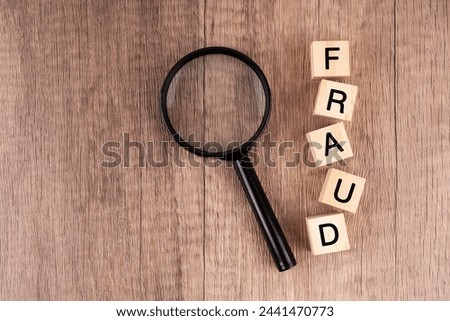 Fraud word on wood block and magnifying glass