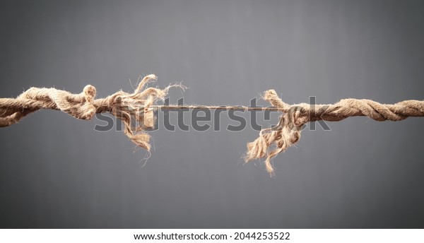 Frayed rope\
about to break on grey background.\
Risk