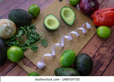 Frazzled face with halved avocado, fresh cilantro, and guacamole ingredients. Top view of food with a frazzled, confused, overwhelmed face. Healthy dieting with natural foods on a wooden background.