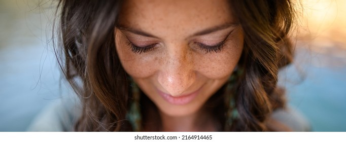 Freckles Woman portrait. Close-up. Beautiful dark haired girl with freckles is looking down on street background - Powered by Shutterstock