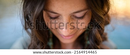 Freckles Woman portrait. Close-up. Beautiful dark haired girl with freckles is looking down on street background
