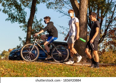 Frederick, MD, USA 10/14/2020: A Group Of Caucasian Teenager Boys Are Hanging Out In The Neighborhood At A Sunny Afternoon. One Is On Bike The Others On Feet. They Wear Face Mask Due To COVID-19.