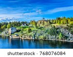 Fredriksborg Castle on a rocky river bank among spring green hills against dramatic sky, Varmdo, Sweden.