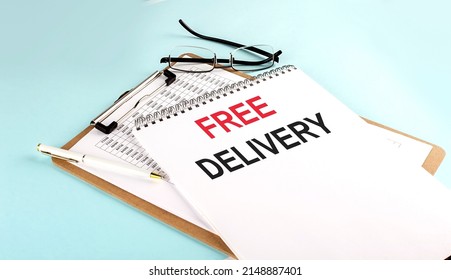 FREE DELIVERY text on notepad on a clipboard with chart on blue background, concept closeup. Business and finance concept