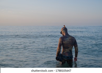 Free Diver With A Camouflage Neoprene Hood, Mask, Snorkel, Dive Fins And Weight Belt, Entering The Water Before Starting To Dive.