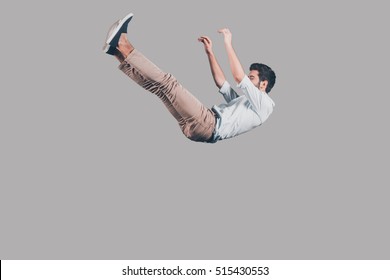 Free falling. Mid-air shot of handsome young man falling against grey background 