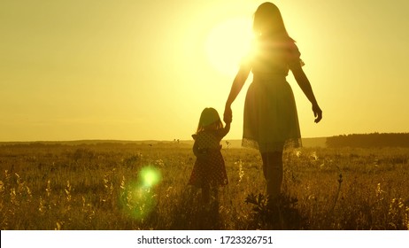 free Happy family with child walks in countryside. healthy Mother and baby are resting in park. happy childhood. little daughter and mother walk across field holding hands. baby holds mom's hand.