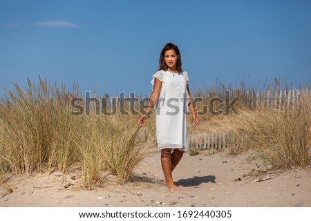 Free happy woman enjoying sun on vacations in dunes.
Concept of happiness, enjoyment and well being. Sea, sand and sun.