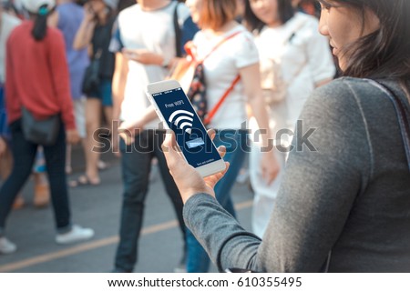 free public Wifi concept.Young woman holding mobile phone on blurred people walking as background