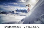 Free ride skier, skiing down steep slope, good background with blue skies and mountains
