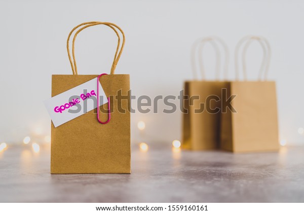 free samples and gifting conceptual still-life,\
shopping bag with price tag with Goodie Bag text on it and other\
bags in the background shot at shallow depth of field with bokeh\
and fairy lights