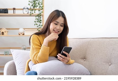 Free time. Asian girl checking social networks on phone, resting on sofa, panorama with free space
 - Powered by Shutterstock