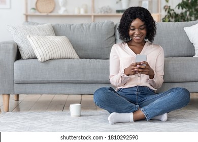 Free Time At Home. Happy Black Woman Resting With Smartphone And Tea In Living Room, Copy Space