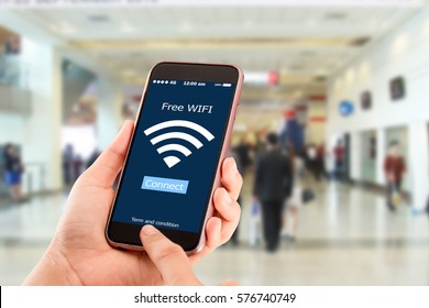 Free wi-fi concept.Hands holding mobile phone on blurred business man walking