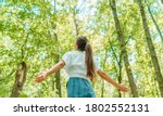 Free woman breathing clean air in nature forest. Happy girl from the back with open arms in happiness. Fresh outdoor woods, wellness healthy lifestyle concept.