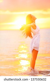 Free woman enjoying freedom feeling happy at beach at sunset. Beautiful serene relaxing woman in pure happiness and elated enjoyment with arms raised outstretched up. Asian Caucasian female model. - Shutterstock ID 137550632