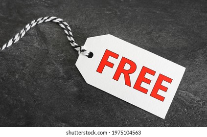 Free word and red sign on a white paper price tag label on dark grey background.