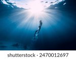 Freediver girl in bikini with diving fins and amazing sun rays.