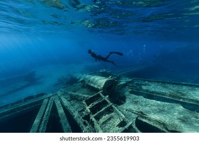 Freediver Swimming in Deep Sea and Exploring Ship Wreck. Young Man Diver Eploring Sea Life.