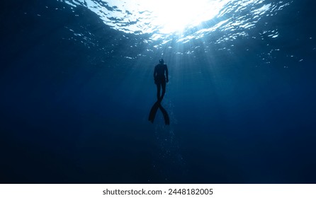 Freediver Swimming in Deep Sea With Sunrays. Young Man DIver Eploring Sea Life.