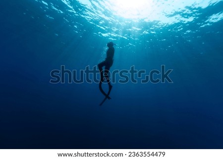 Freediver Swimming in Deep Sea With Sunrays. Young Man DIver Eploring Sea Life.
