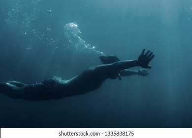 Freediver Young Man Swimming Underwater And Using Breaststroke Technique.