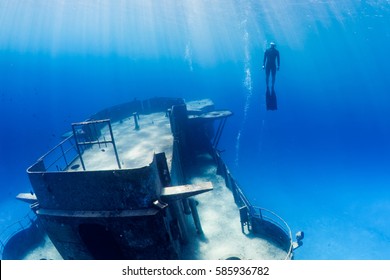 Freedivers Swimming Through A Large Underwater Shipwreck