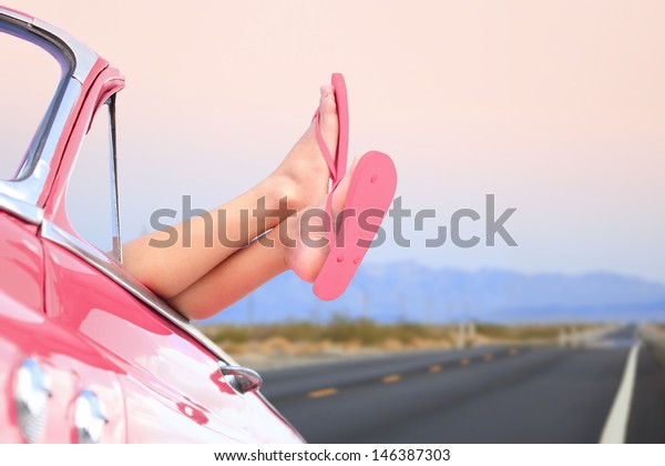 Freedom car travel concept - woman relaxing with\
feet out of window in cool convertible vintage car. Girl relaxing\
enjoying free holidays road\
trip.