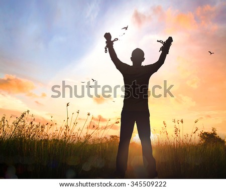 Freedom concept: Silhouette human hand broken chains against twilight sky autumn sunset background