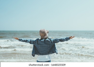 Freedom feel good and travel adventure concept. Copy space of woman raise hands with blue sky and wind wave on beach background. Vintage tone filter effect color style.